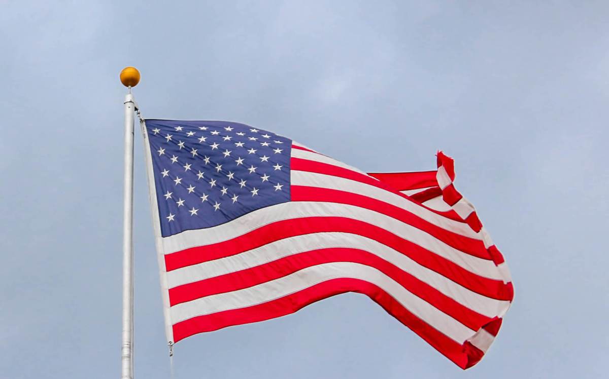 usa-flag-waving-on-white-metal-pole-1550342