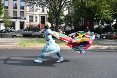 A child walks along Eastern Parkway drapping Carribean Nations.