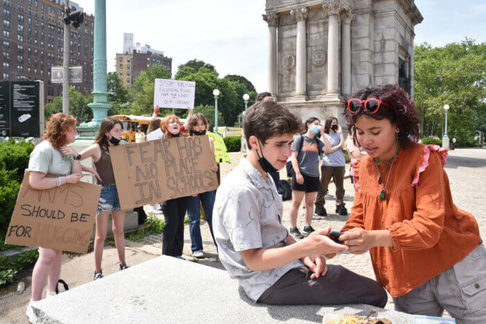 students talk and hold cardboard signs at grand army plaza gun control protest