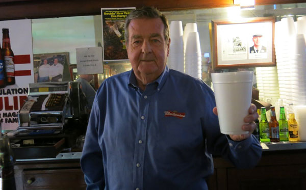 james houlihan holds up a cup behind the bar at farrell's