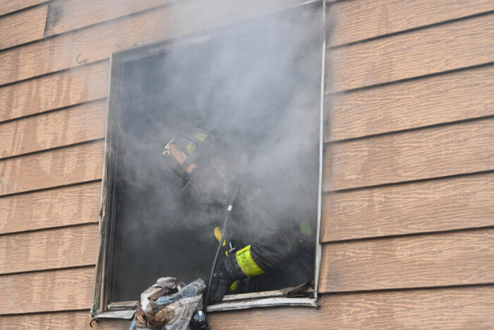 firefighter leans out of smoky window