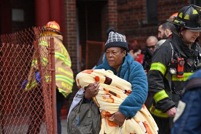 A man carries a child away from a fatal fire in Crown Heights.