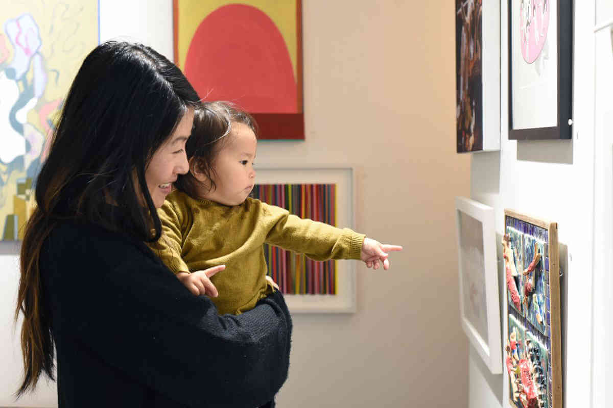 A woman and child admire artwork at an exhibition held by the Brooklyn Arts Council.