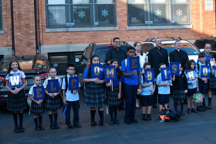 Pupils clad in school uniforms pose with Bishop Brennan